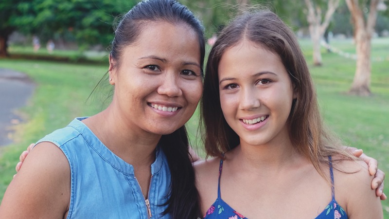 Support worker with arm around young person looking at camera